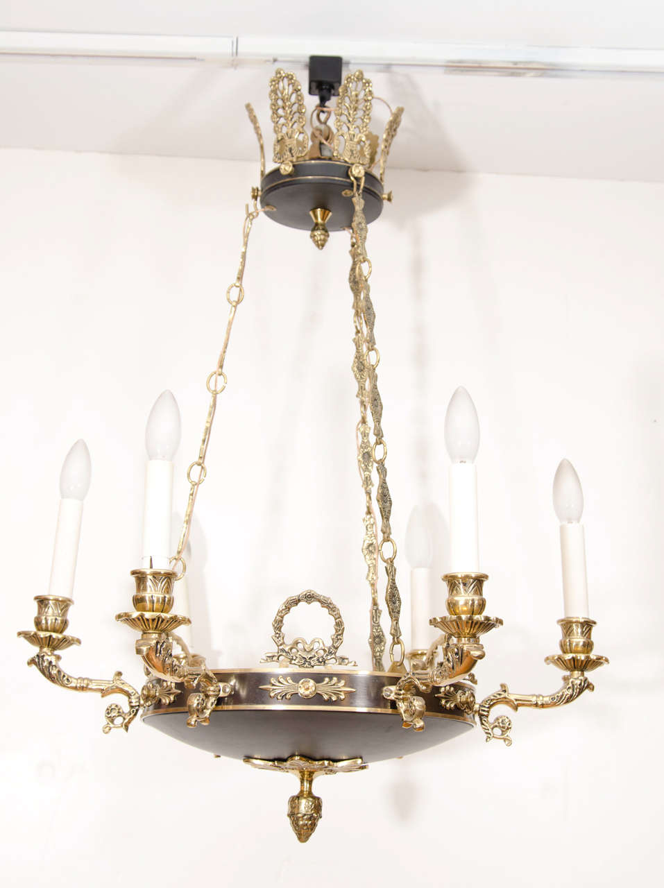 Patinated brass and brass details copied from the pre-electricity Gustavian period, featuring six faux candles hanging on three decorative brass chains, surmounted by a 