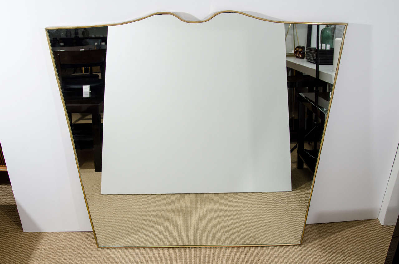 Modernist horizontal mirror with a curved shaped top brass frame.