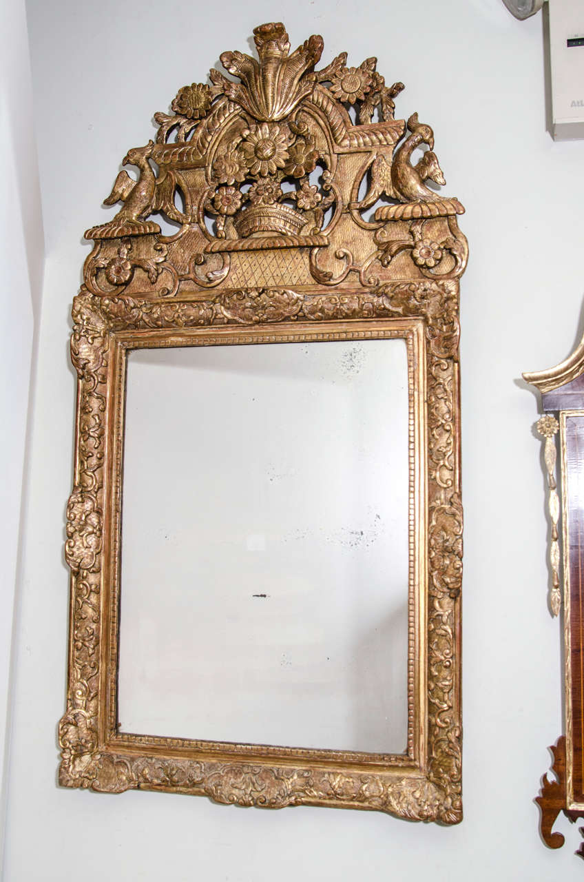 Miroir en bois doré sculpté de style Régence avec des plumes, des aigles, des fleurs et d'autres éléments sculptés.