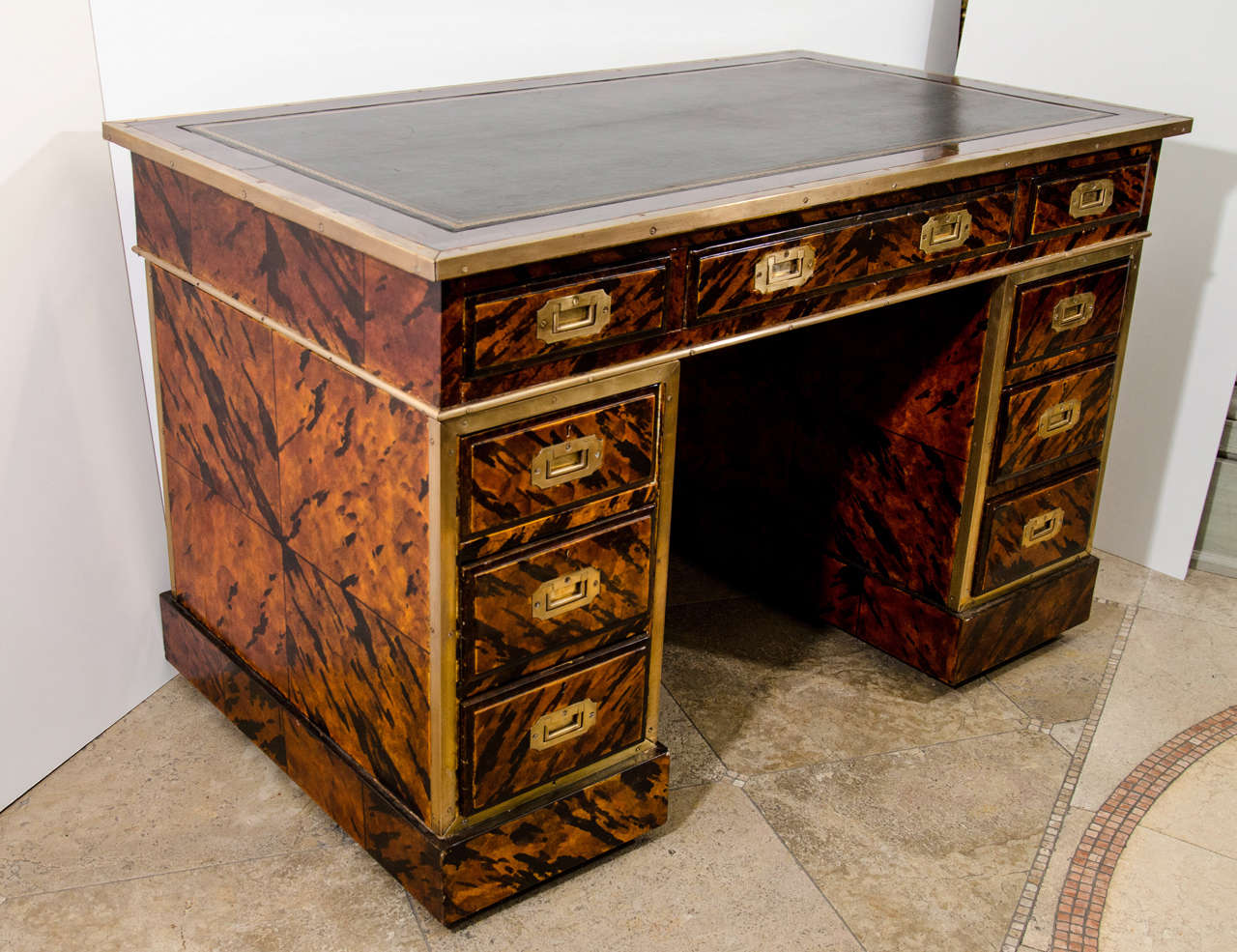 An unusual English campaign form leather top desk with brass trim and mounts and decorated with faux tortoise shell on a square plinth base.