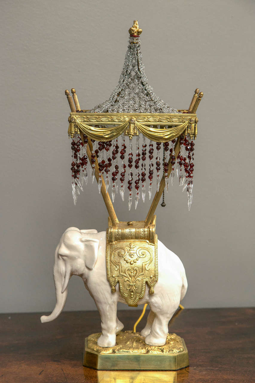A rare French porcelain and bronze elephant mounted as a lamp with a beaded shade.