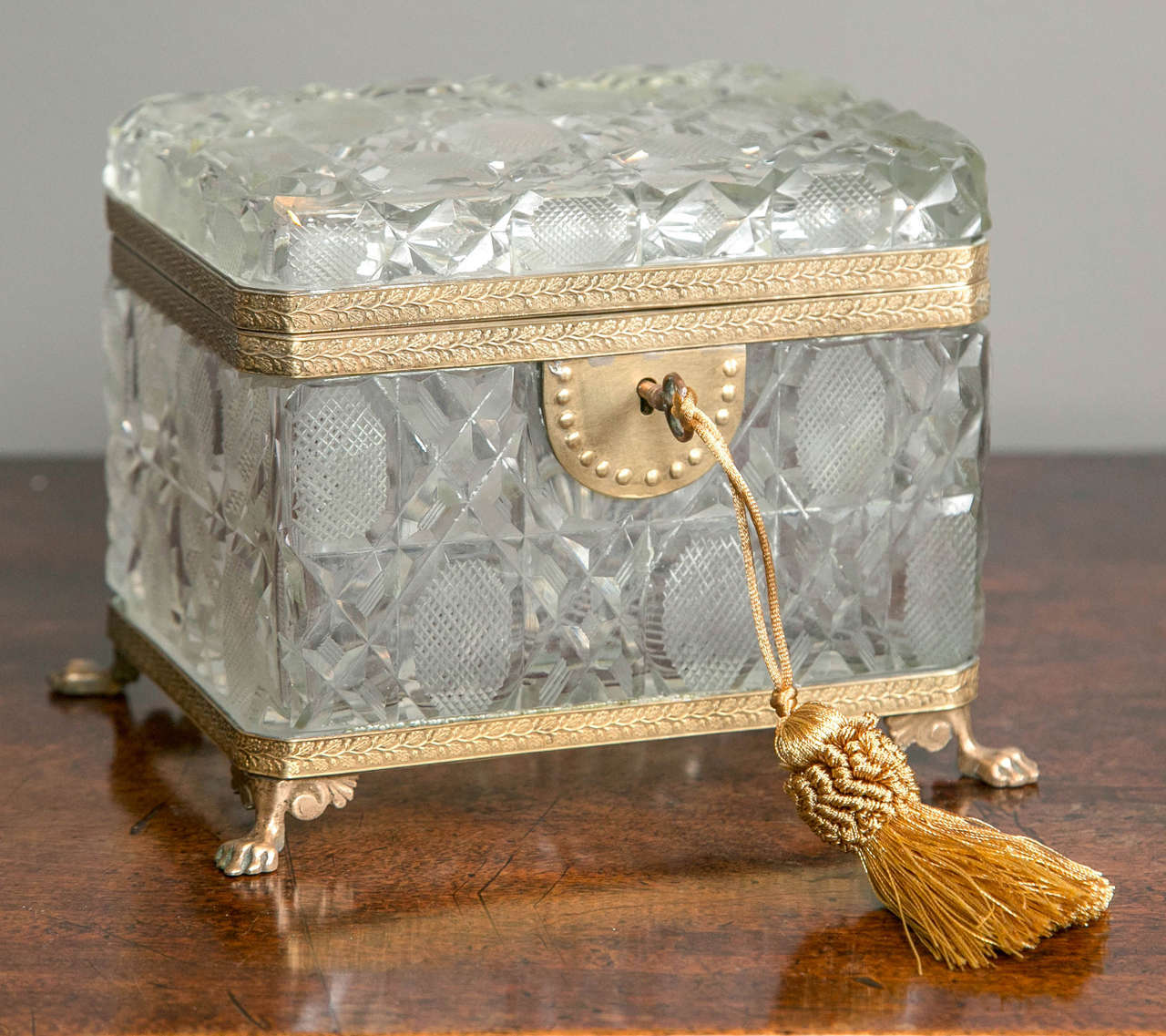 A large antique cut crystal box with bronze mounts and feet with a key.
