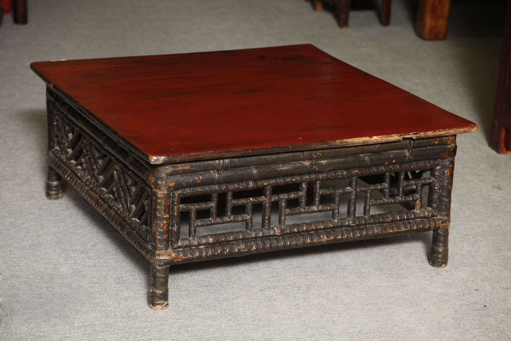 A petite Chinese 19th century coffee table made of bamboo with red lacquered square top. This low coffee table comes from China, where it was made with bamboo and lacquered wood during the 19th century. The top is nicely varnished with a red