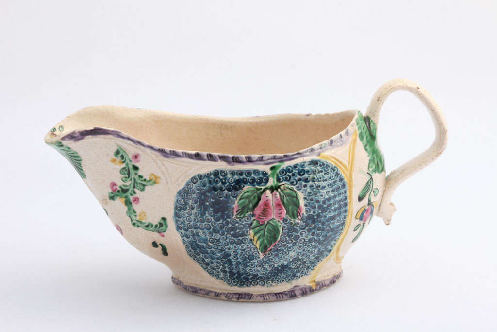 A rare and fine English saltglazed stoneware sauceboat molded with raised leaves and fruit and brightly painted in enamel colors
