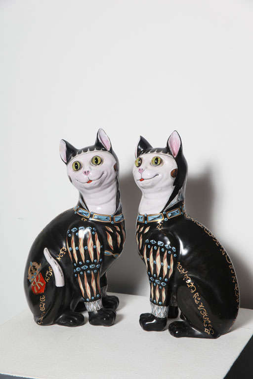 A rare pair of Galle faience cats painted with Heraldic decoration, one signed EG on foot