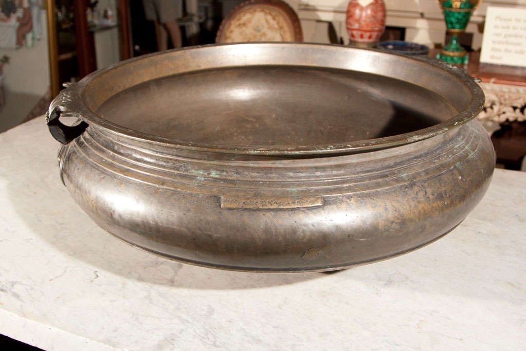 A  MASSIVE ROUND  BRONZE RICE BOWL ON 3 STUBBY FEET, WITH MODELED HANDLES AND INSCRIPTION