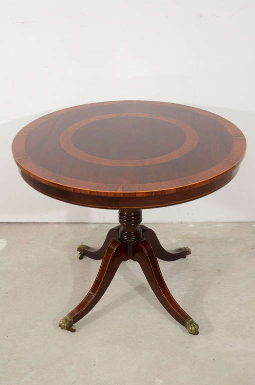 A fine regency mahogany and rosewood veneered and cross banded center table, the circular top with beautifully veneered concentric ring decoration,crossbanding and satinwood line inlay, above a veneered frieze raised on a tapering central standard,