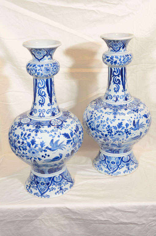 Provenance:From the collection of Katherine Mellon
 A pair of large Dutch Delft Blue and White vases with all around scenes of songbirds in a flower filled garden. At the top and bottom  and on the shoulder are bands of scrolling vines and flowers