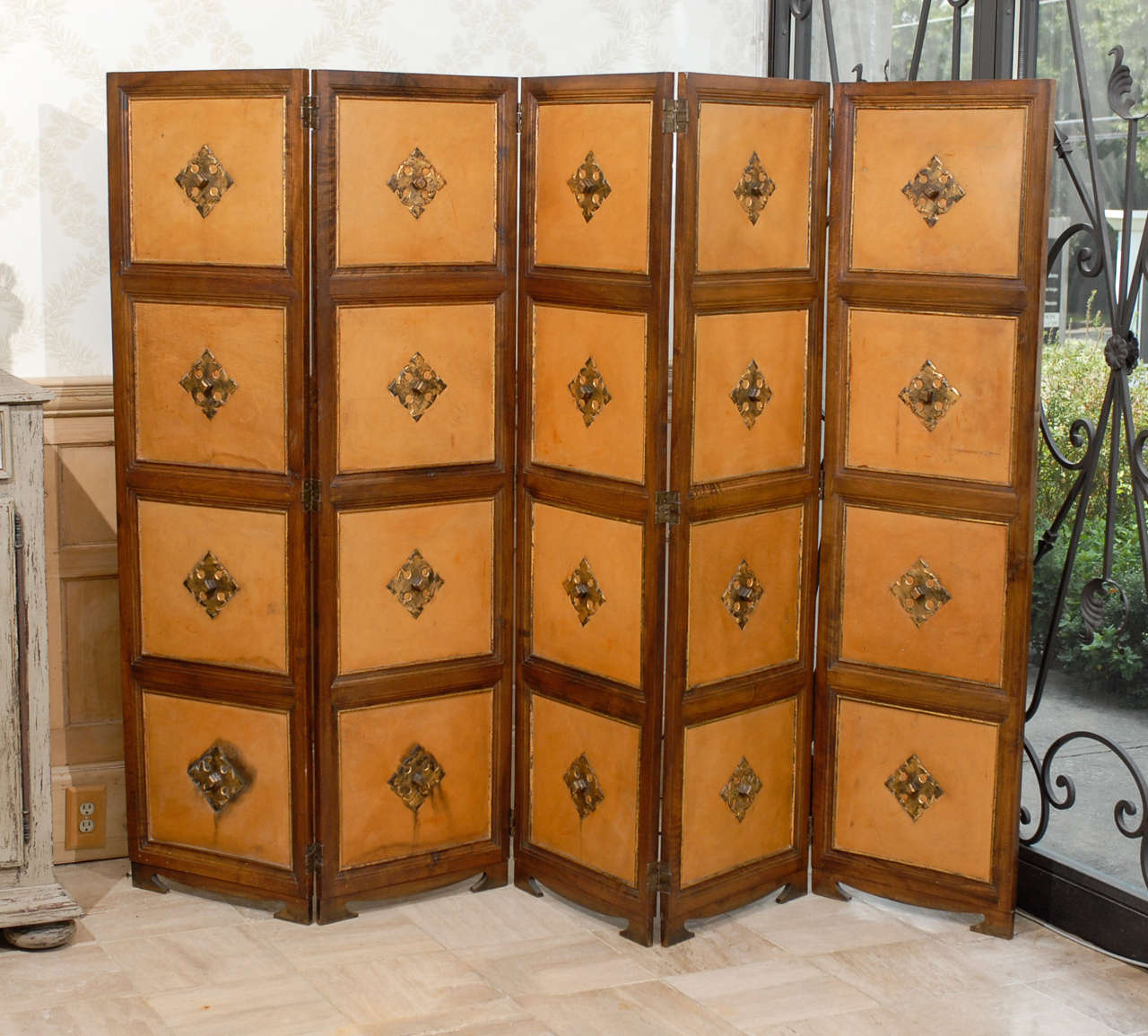Vintage French Five Panel Folding Screen, Circa 1940
This vintage French screen gives off a more monotone look .  On one side, each leather square has a center medallion, and the other side has solid walnut with a smaller medallion. The five tall