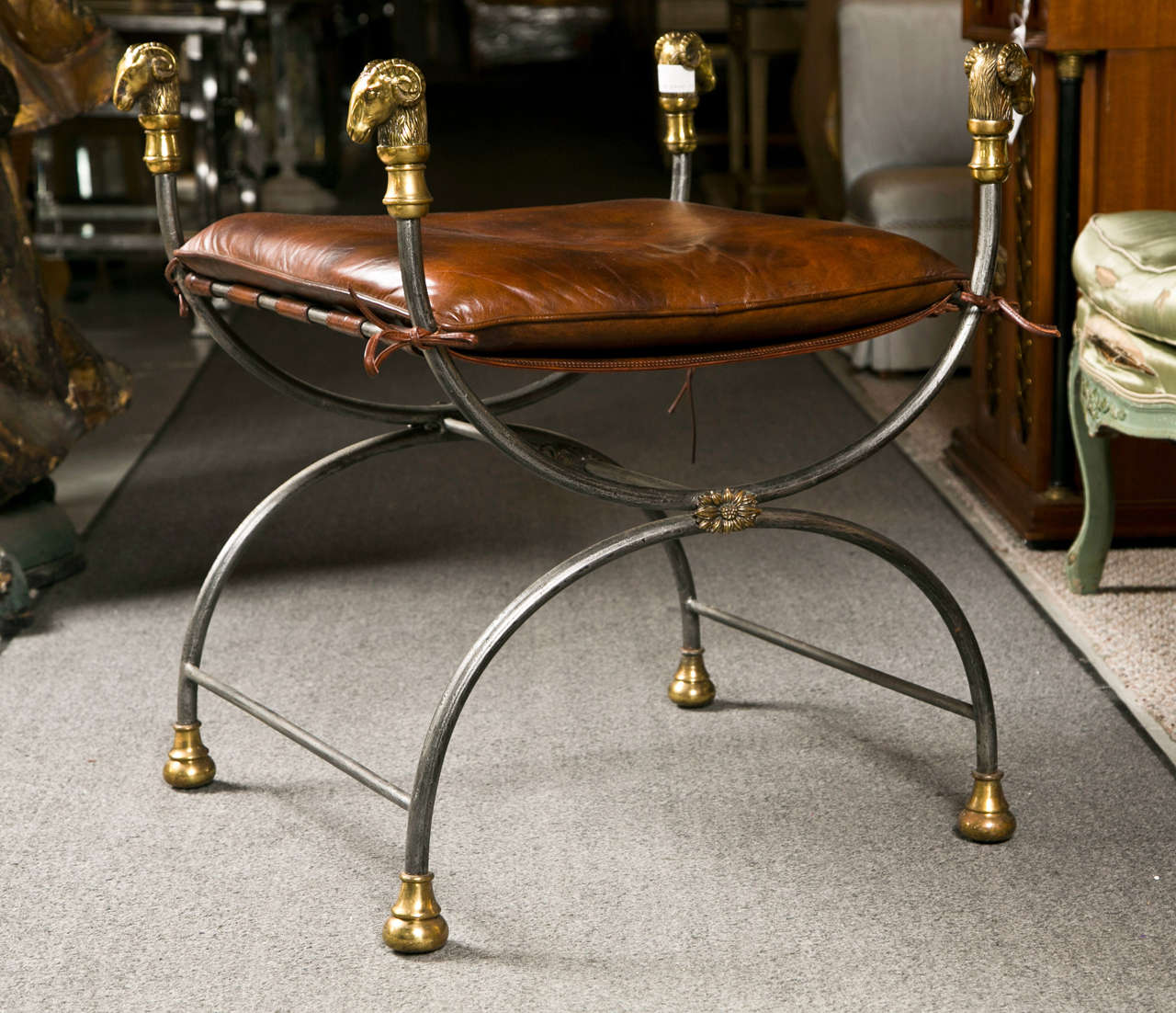 French Directoire style bench, bronze and steel in curule form, removable leather cushion, decorated with parcel-gilt four rams' heads.