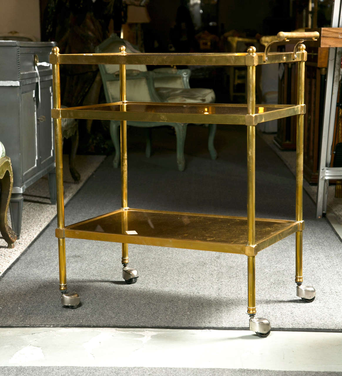 French Art Deco style gilt-brass tea cart, circa 1960s, has a total of three gilt-glass tops, rolling on castors.