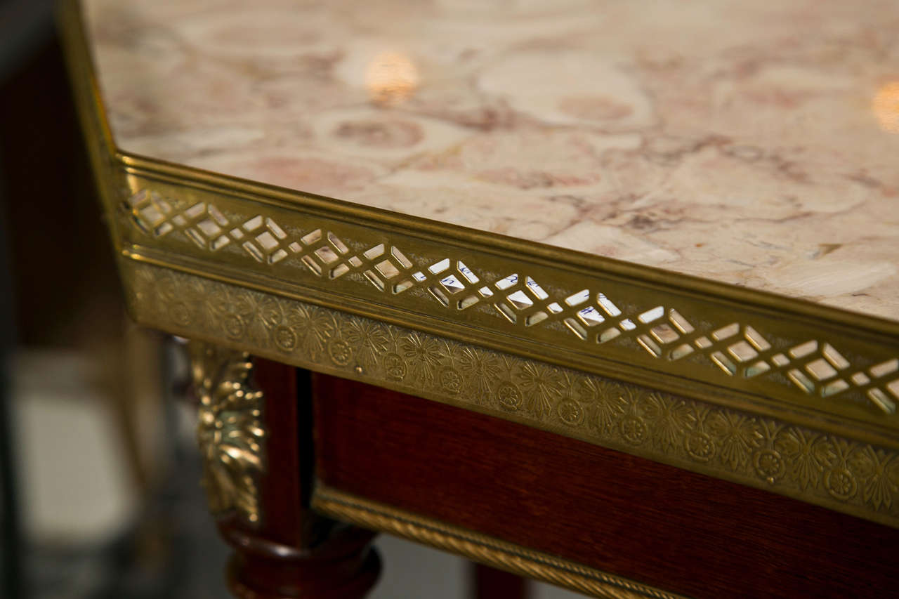 French rosewood end table, circa 1930s, the octagonal marble top with pierced gallery atop a narrow frieze decorated with bronze mounts and finials, supported on four legs extending to splayed feet joint by a lower tier.