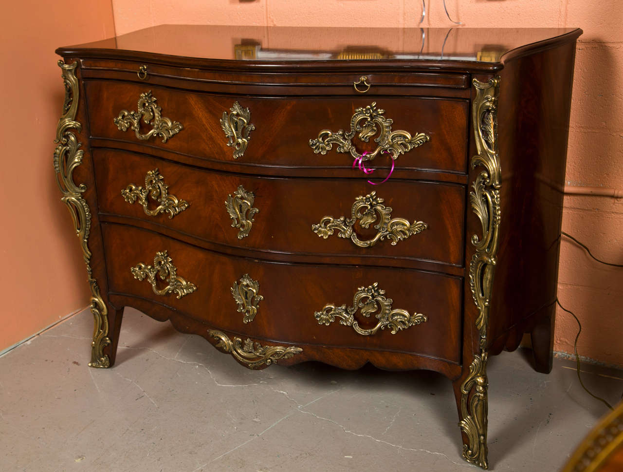 Pair of mahogany commodes by Ralph Lauren in the French Rococo taste, the serpentine top over a bombe form case fitted with three drawers, the top also has a pull-out tray, decorated with elaborate bronze mounts and handles, raised on splayed feet,
