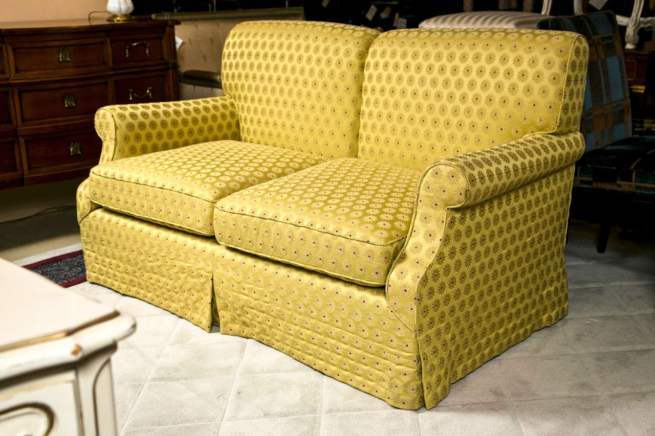 An English Provincial style loveseat sofa, 3rd quarter of 20th century, fully upholtersed in embroidered gold fabric. Cushioned seat, rolled arms. Possibly Baker.