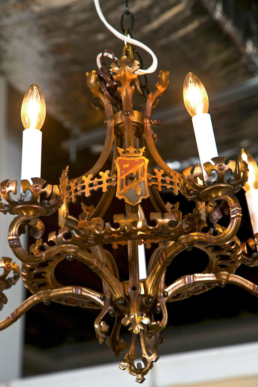 Pair of 5-light iron chandeliers/fixtures, circa 1950s, in the Tudor style, each patinated, decorated with coat of arms medallions.