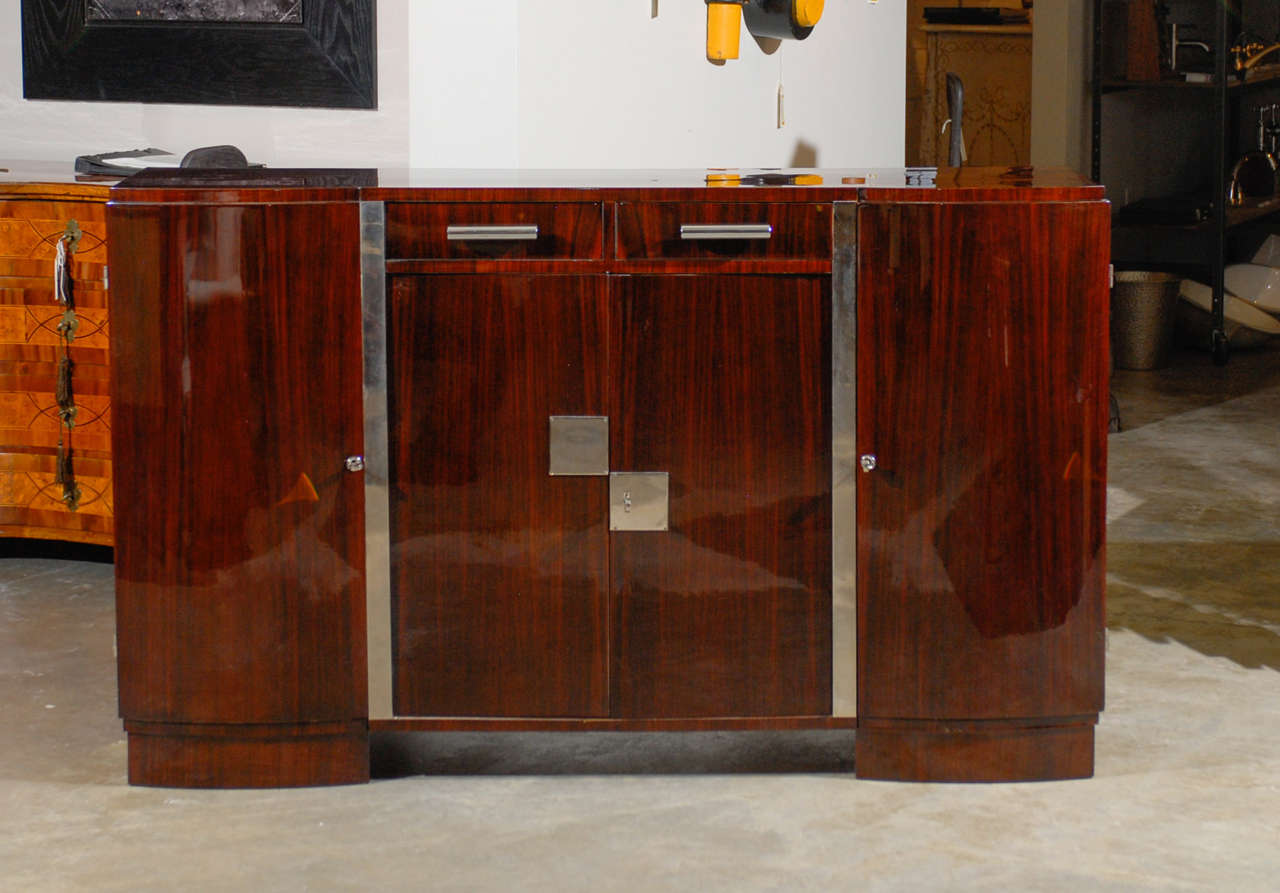 A French Art Deco style palisander sideboard with chrome accents from the 20th century. This exquisite French sideboard features a rectangular shaped top over a lustrous body, made of two dovetailed drawers and two side cabinets flanking a central