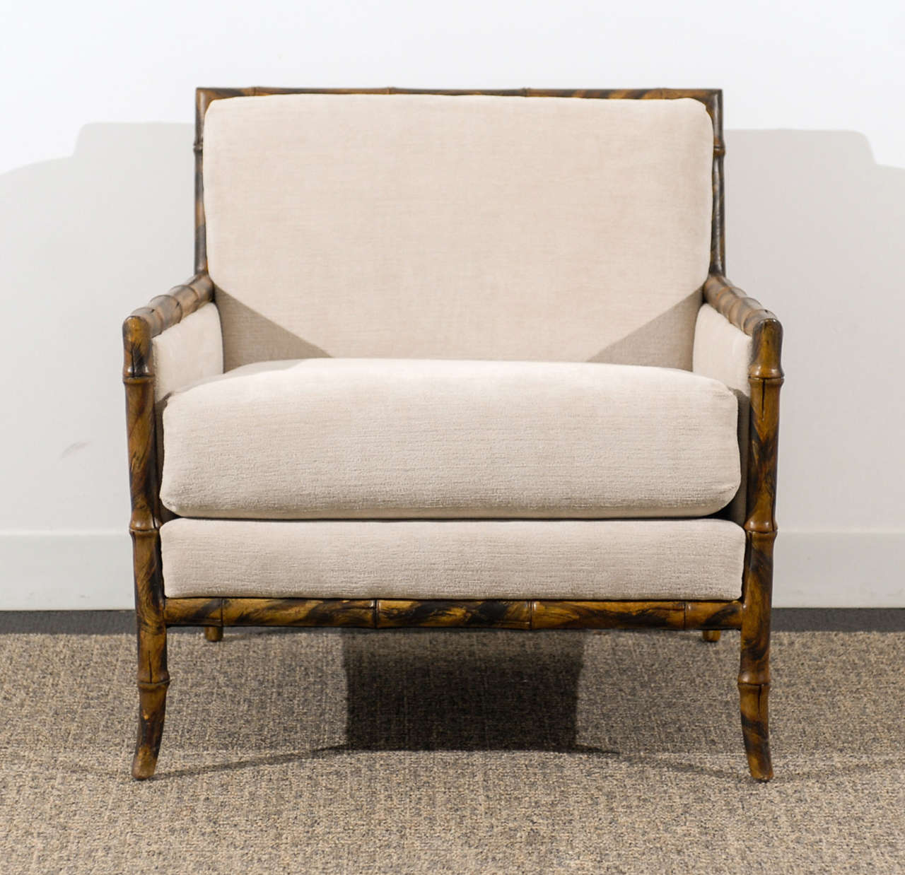 An absolutely beautiful pair of faux bamboo lounge/club chairs. Faux tortoise shell finish with cane panel inset. A slight saber detail to the leg. Upholstered in cut linen velvet. While the chairs are unmarked, they are reminiscent of
