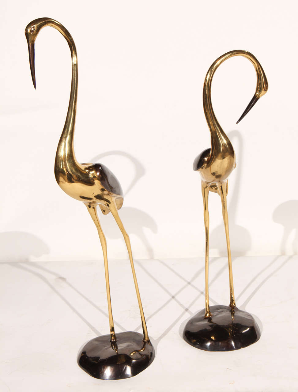 Pair of vintage brass and black chrome cranes. Note that there is some scruffing on the bases. One crane is 26.5 inches tall and the other is 23 inches tall.