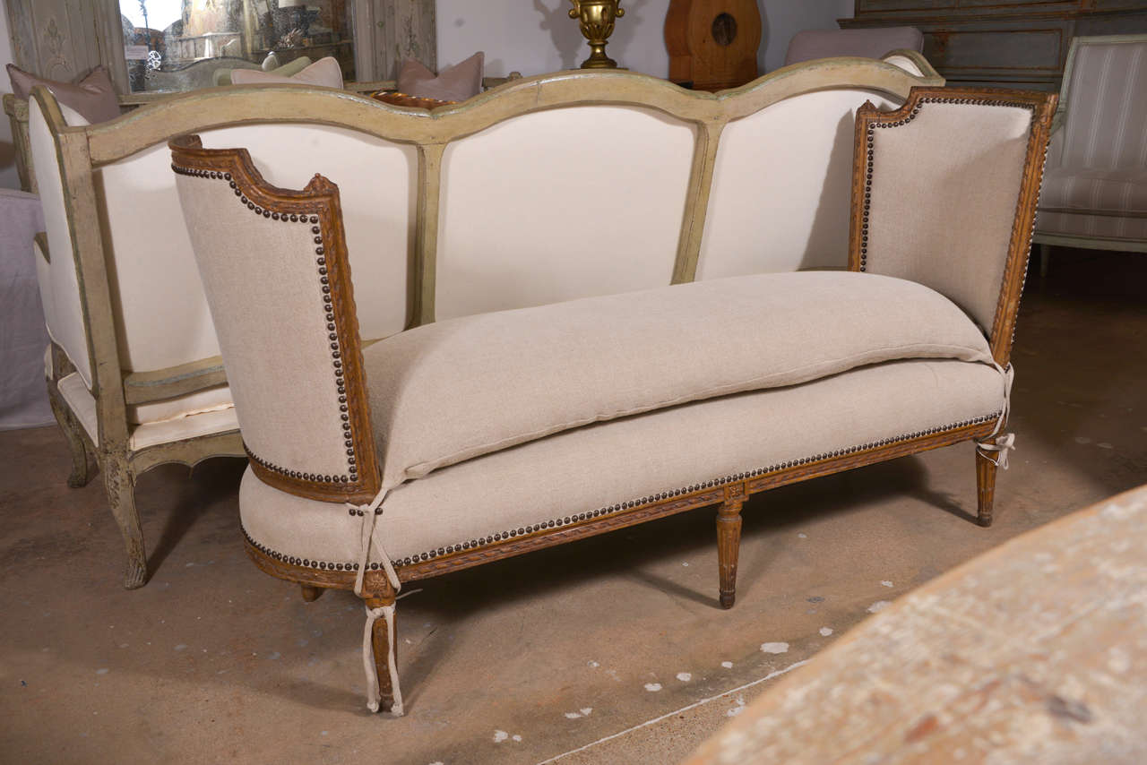 Louis XVI bench, beautifully carved, with gently curved shield-shape ends, fluted tapered legs, ribbon-twist molding and newly upholstered in linen with a tie-on cushion.