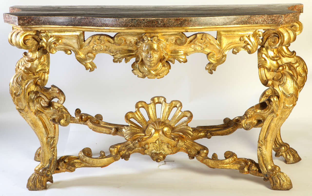 A fine pair of italian mid-18th century giltwood  consoles
each with a  painted porphire  marble top , above a pierced frieze centred by a mask , on cabriole legs with scrolling acanthus leaves and palmettes, joined by an 'X'-shaped stretcher