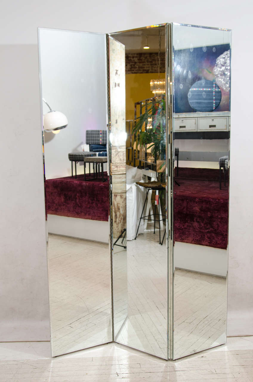 Pair of mirrored screens or room dividers. The screens are mirrored on one side and are clad in white laminate on the reverse side. Each of the three panels in each set measures 18 inches. The measurement for the width listed below is for one of the