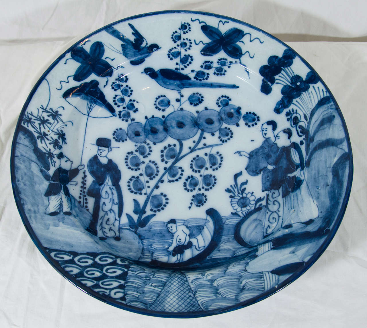 A pair of 18th Century Dutch Delft blue and white chargers hand-painted in a distinctive design with figures covering the entire dish. This borderless design is quite rare. The back of the plate marked 