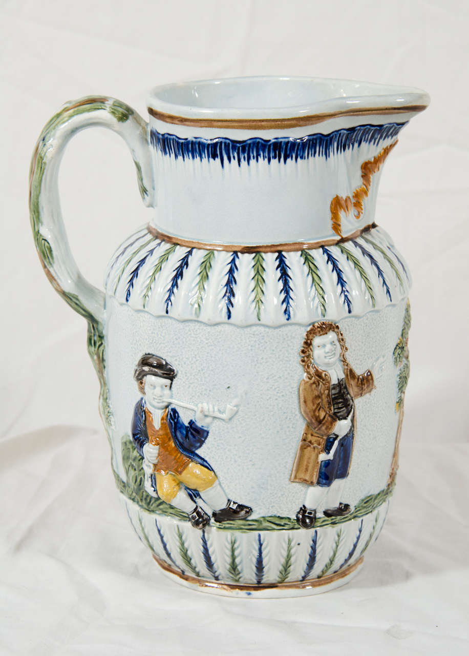 A late 18th century Prattware pitcher, relief molded, with typical Pratt colors. The scene shows the parson, the clerk and the Sexton smoking and drinking. The relief work of the figures is very crisp as is the blue feather edging along the