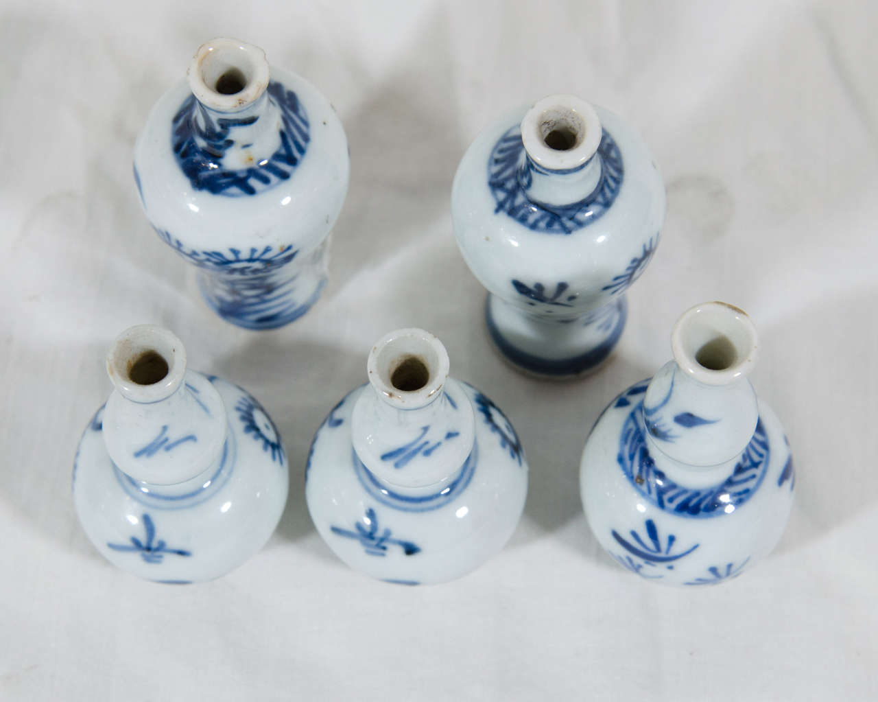 A Kangxi miniature Blue and White five piece garniture comprising a pair of baluster vases and three double gourd vases. It is decorated with simple flower sprigs painted in tones of cobalt blue.