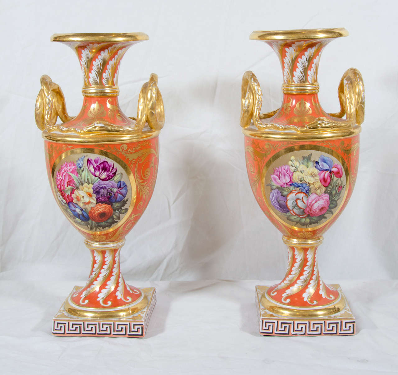It is rare to find a pair of vases that has so many outstanding elements of Regency style, exquisite execution of finely painted flowers with an unexpected use of pink, blue and violet against a strong orange ground, beautifully gilded snake