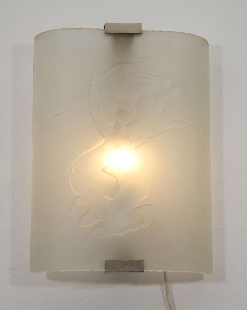 Curved, frosted and etched with a voluptuous rendering of Diana, Roman goddess of the hunt, her bow and prey. The sculptural light is affixed to her wall plate with brushed metal hardware and holds one 60 watt bulb.