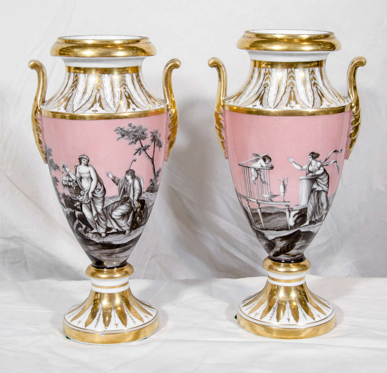 This exquisite pair of 18th century Locre vases shows romantic scenes with classical figures on a pink ground. In one scene a young woman implores Cupidt o escape from his cage and come to her. The other vase shows a romantic scene with a shepherd