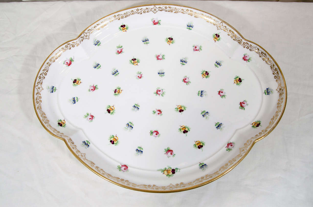 A Minton porcelain tray for serving decorated all-over with delicate small roses and pansies. A gilded vine leaf border outlines the lobed edge.