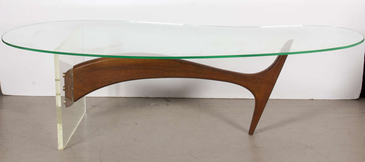 Table is a bold sculptured strut of carved walnut piercing a lucite block, supporting a kidney shaped glass top. The form smis inspired by Kagan and of the period, but the designer is not known. Original excellent condition throughout. Anerican, mid