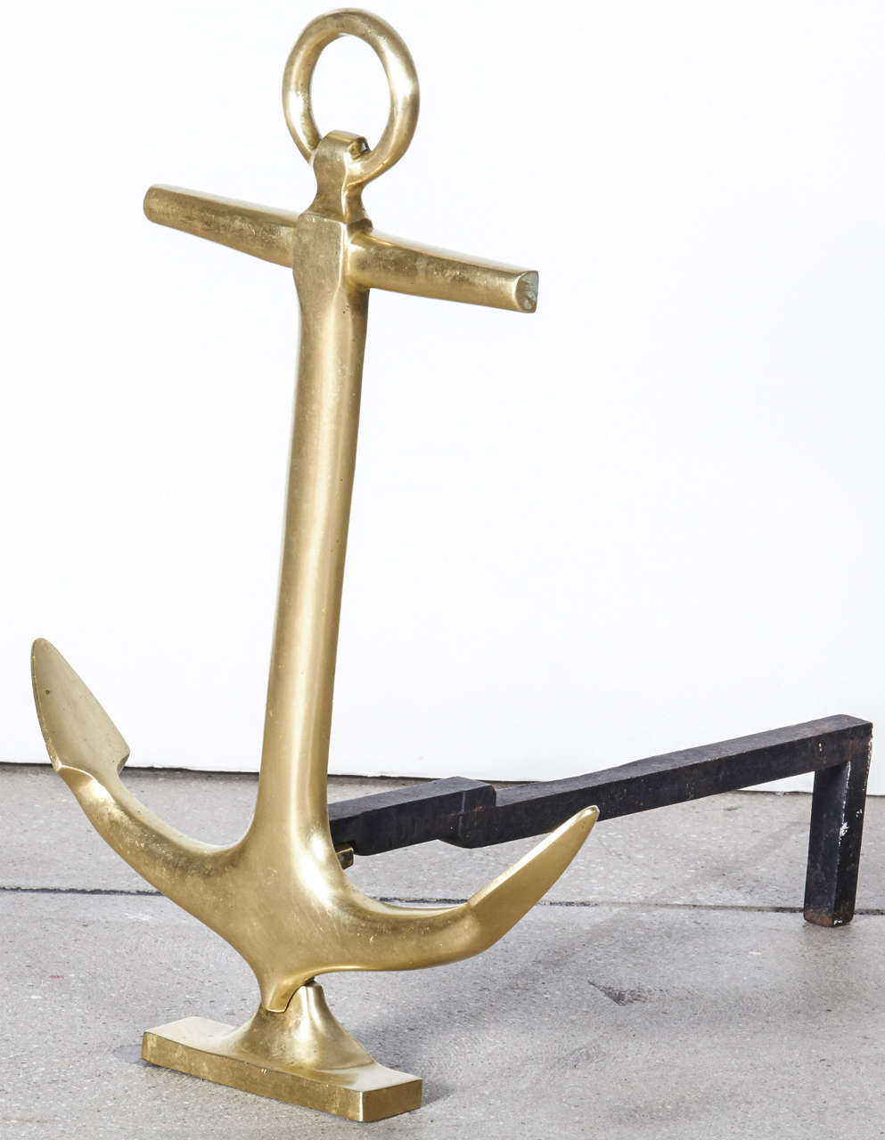 Pair of anchor-shaped andirons in polished brass with black iron stand.  USA, circa 1940.
