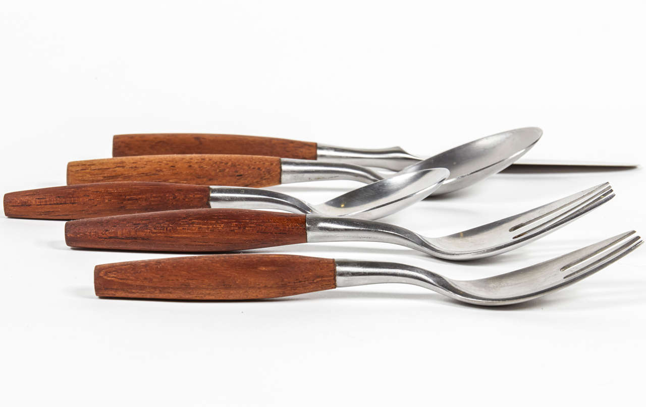 A five-piece place set in the Fjord pattern by Jens Quistgaard for Dansk.  Denmark, circa 1960.  Certain pieces signed.  Stainless steel with teak handles.  Priced per five-piece place setting; up to 12 place settings available.
One place setting