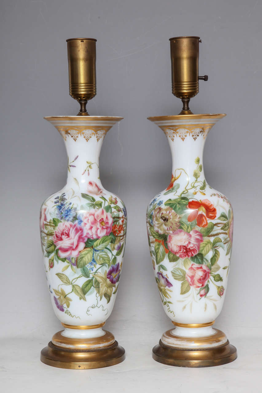 A pair of antique baccarat opaline finely painted vases turned into lamps, painting attributed to Jean Francois Robert. Of baluster form, each finely painted with a lush bouquet and a flower spray, the neck enriched with gilt work, as well as edged