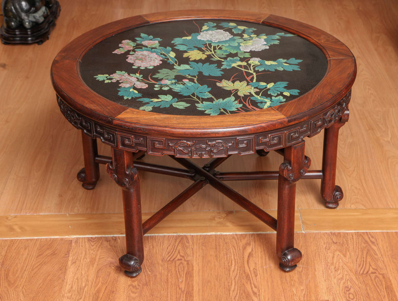 Ancienne table basse circulaire en bois de rose sculpté et émail floral cloisonné. Les pivoines roses et les feuilles vertes sont mises en valeur par le fond noir d'encre. Le bois de rose est sculpté en formes géométriques avec des pieds façonnés,