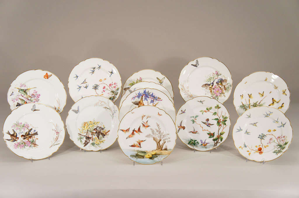 This is a lovely set of 12 uniquely painted dessert plates with a variety of subjects. They feature birds and butterflies done with a transfer border and hand painted polychrome enamels. The shaped rims are highlighted in gold and each plate tells a