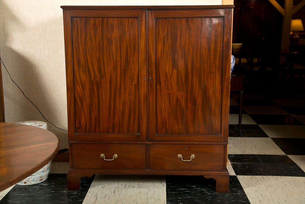 Cette armoire à deux portes et deux tiroirs / presse à linge en acajou finement grainé est juste la bonne taille pour cette chambre d'amis sans placard. Pas trop grand pour ne pas prendre trop de place, mais assez grand pour contenir les tenues