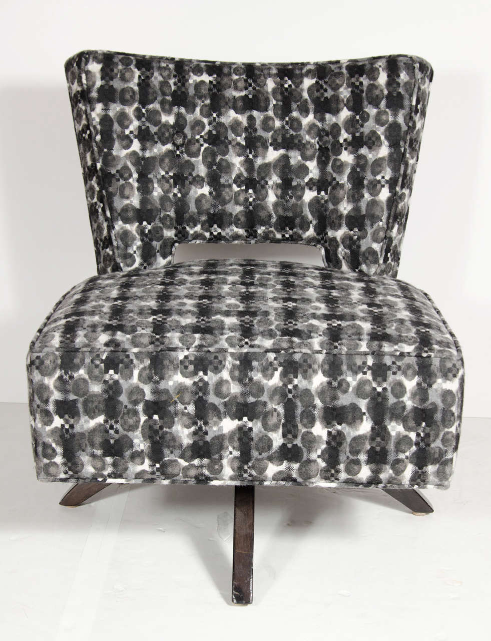 This striking Mid-Century Modern swivel slipper chair features a cut out back with textured black & white upholstery covering the entirety of the chair and back. The chair also features splayed ebonized walnut legs . This modernist design makes for
