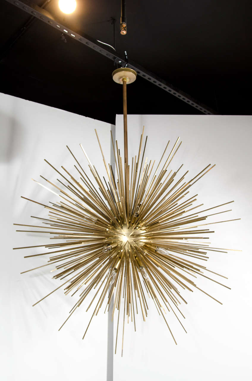 This incredibly stunning chandelier was a one of a kind custom piece that was used in the lobby of a public building. It has multi gilt rays emanating out of a gilded bronze sphere fitted with 16 candelabra based bulbs. The word spectacular does not