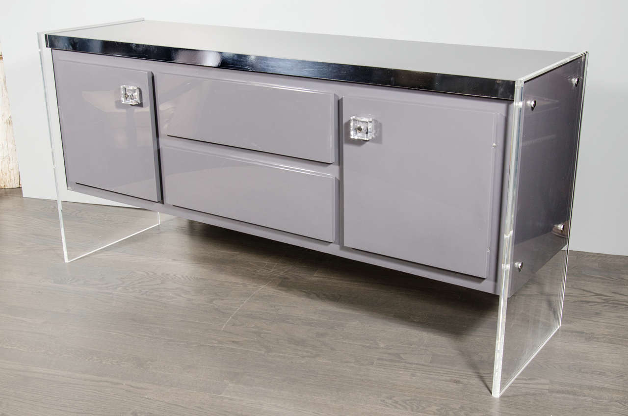 This outstanding cabinet is designed by Milo Baughman for Thayer Coggin. The cabinet is supported by two slabs of lucite and has been newly re-lacquered in a warm grey. The slimline lucite slabs give the illusion that it is floating.  It features