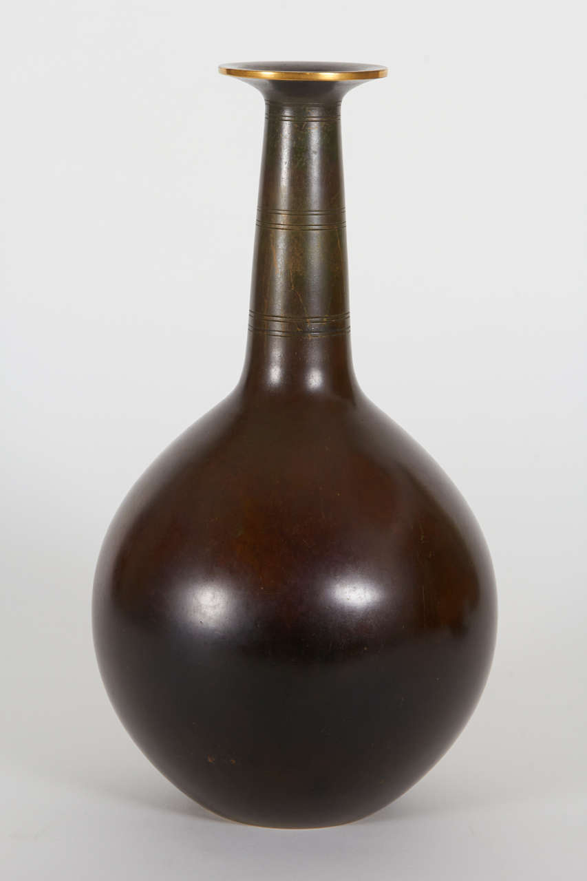 JUST ANDERSEN   (1884-1943)  Denmark

Grand vase  c. 1935-40

Rich deep brown patinated bronze, neck with three sets of four incised lines, with flaring rim and gilt edge

Marks: DENMARK, JUST (in a triangular cartouche), No. B 2055

For