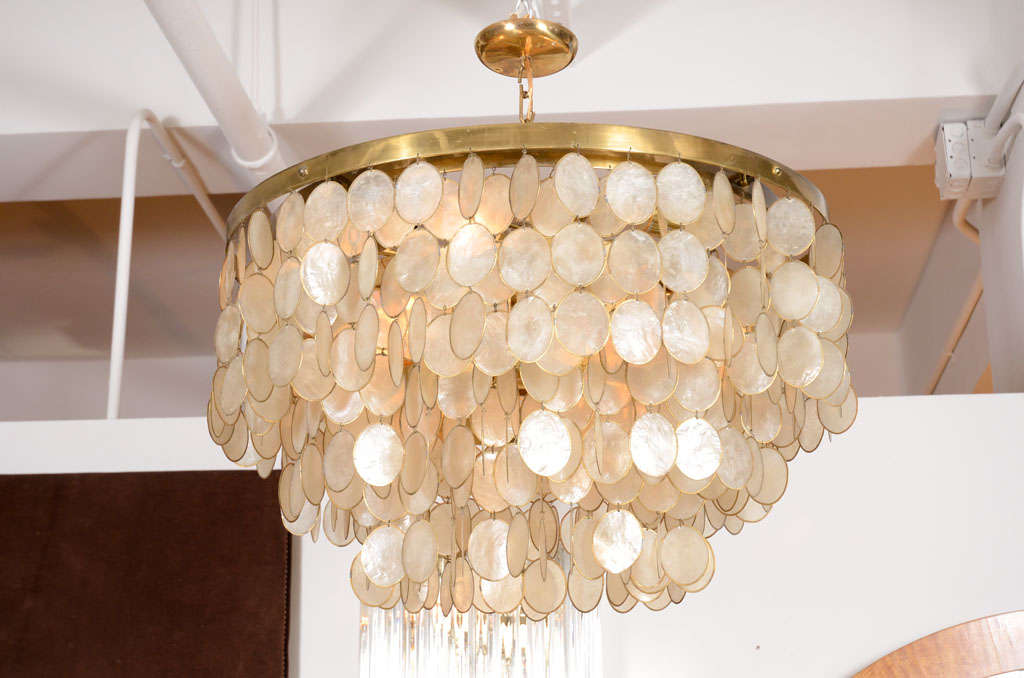 A vintage chandelier comprised of a brass frame with six concentric circles descending in size to form three tiers, each circular frame has dangling links of oval capiz shells set in brass bezels.  After Verner Panton.  American, circa 1960's