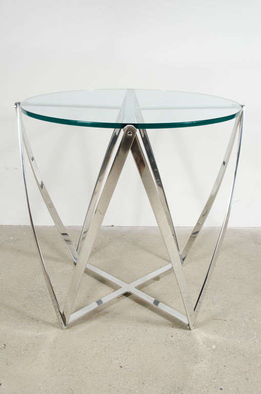 A graphic lamp table with base comprised of polished aluminum ribbons in a criss-cross array, supporting a circular glass top. By John Vesey. U.S.A., circa 1960.