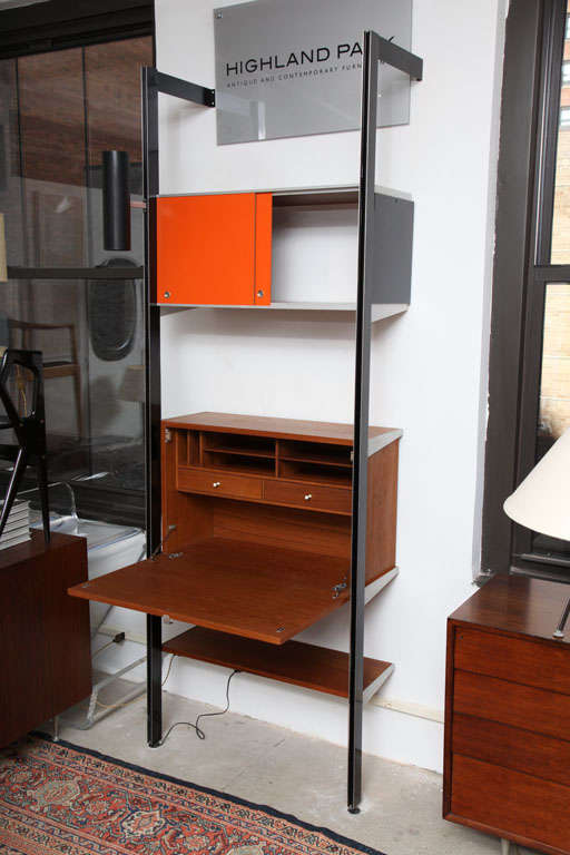 George Nelson's 'Comprehensive Shelving System' for Herman Miller comprised of two uprights, rear hanging drop-front secretary with pigeon hole storage and two drawers with porcelain drawer pulls, open back sliding door case with black finish side