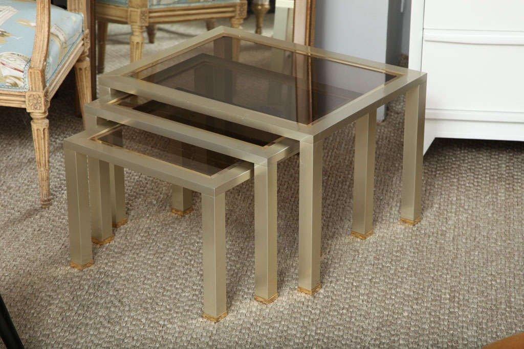 A sleek trio of brushed chrome and brass nesting tables with tinted glass tops, clean and pretty.