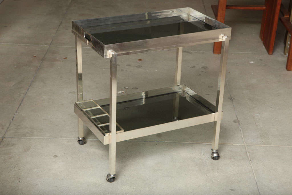 A very sleek and chic two-tiered silver plated bar cart on casters.  The cart has two tinted glass shelves and has silverplate markings attributed to Christofle.