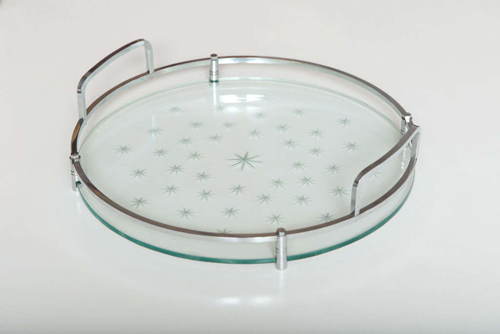 Pale green glass engraved with stars, mounted in a circular polished chrome frame. Minimal and elegant