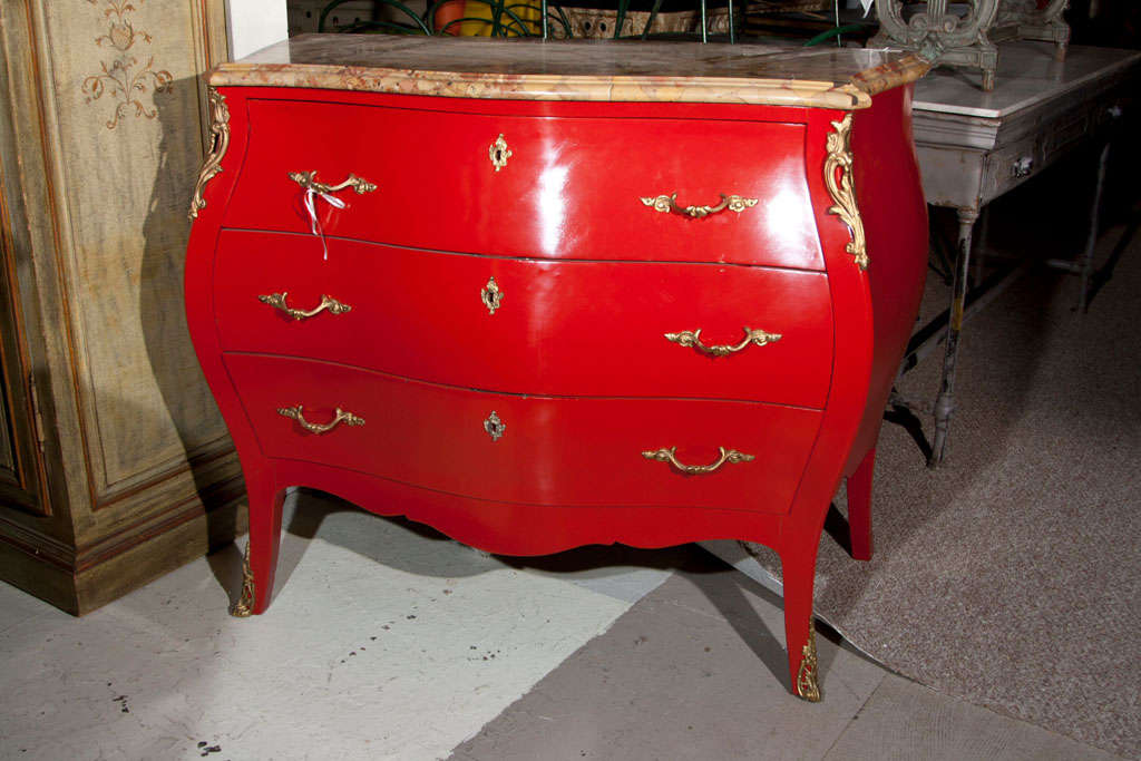 A French Louis XV style Bombe commode, the beveled marble over a red lacquered case fitted with three drawers.